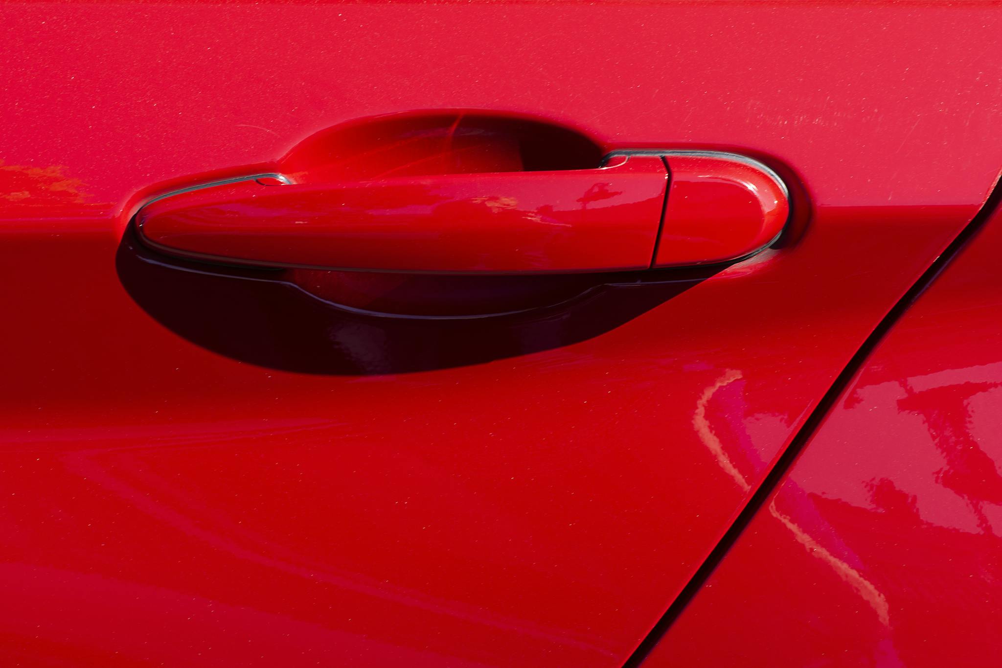 Detailed close-up image of a red car door handle with vibrant color and sleek design.